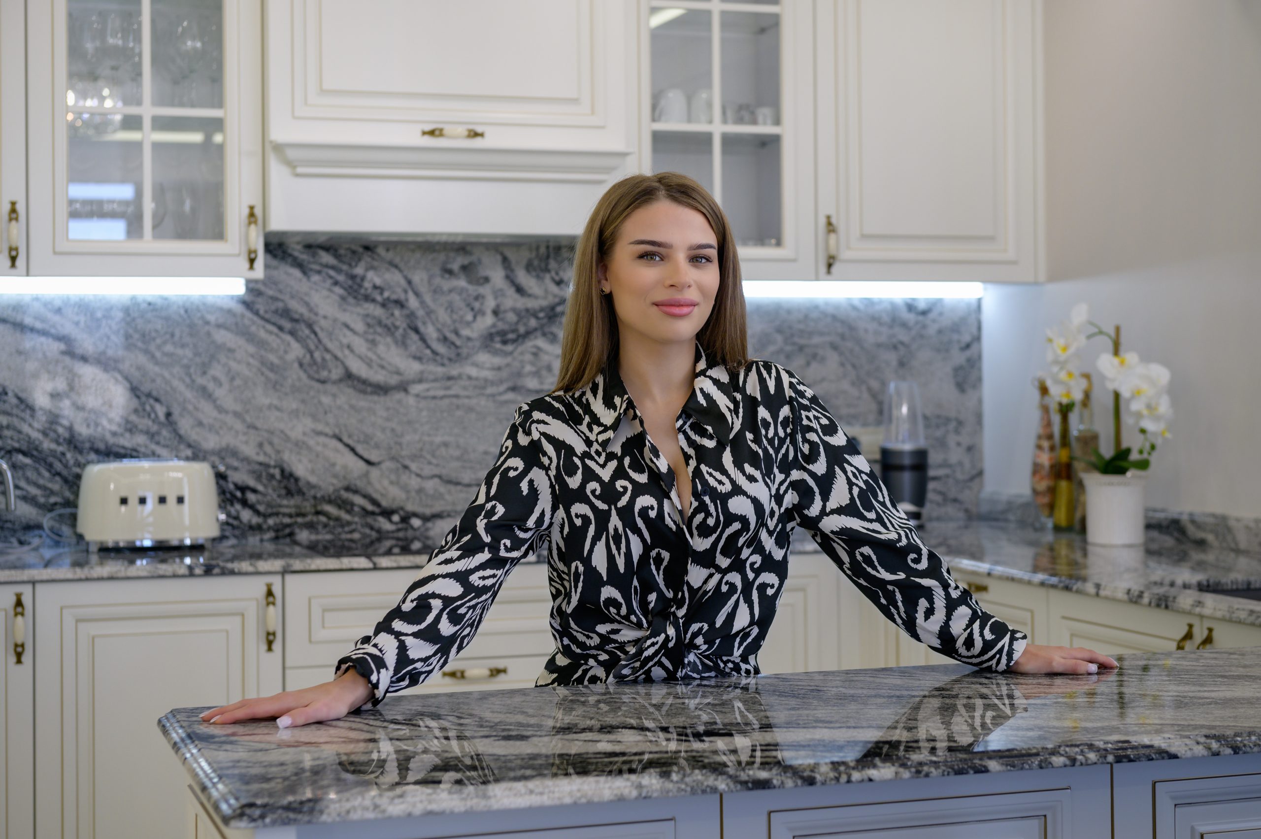 A woman poses in a kitchen with a traditional and sleek design